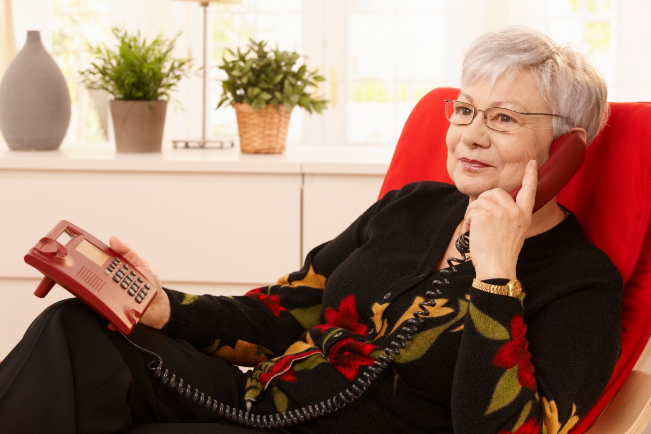 Mevrouw aan de telefoon in een rode stoel Mevrouw aan de telefoon in een rode stoel